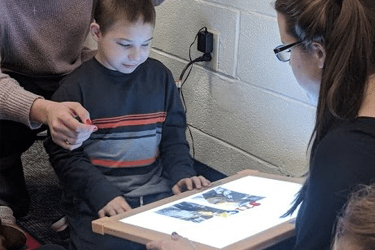 Teachers helping deaf-blind student with a light box