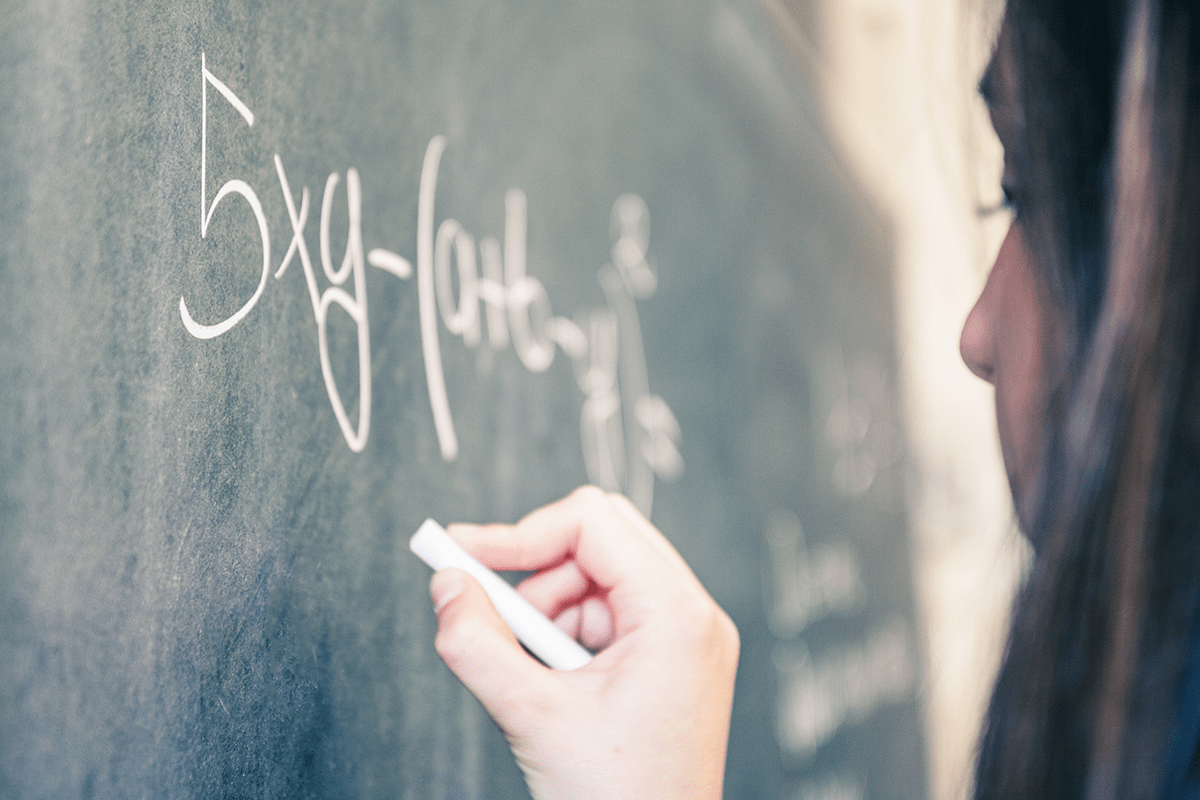 girl writing an algebra equation on the chalkboard