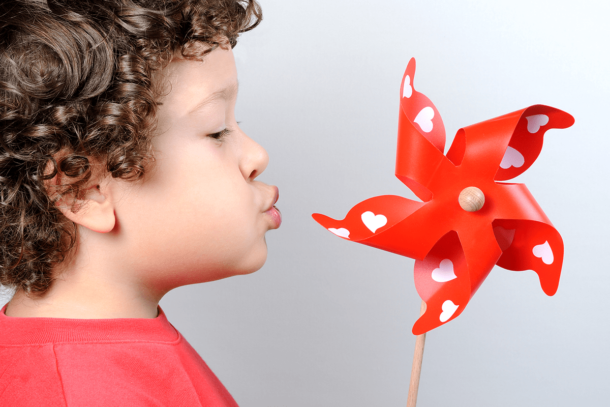 child blowing on a toy pinwheel