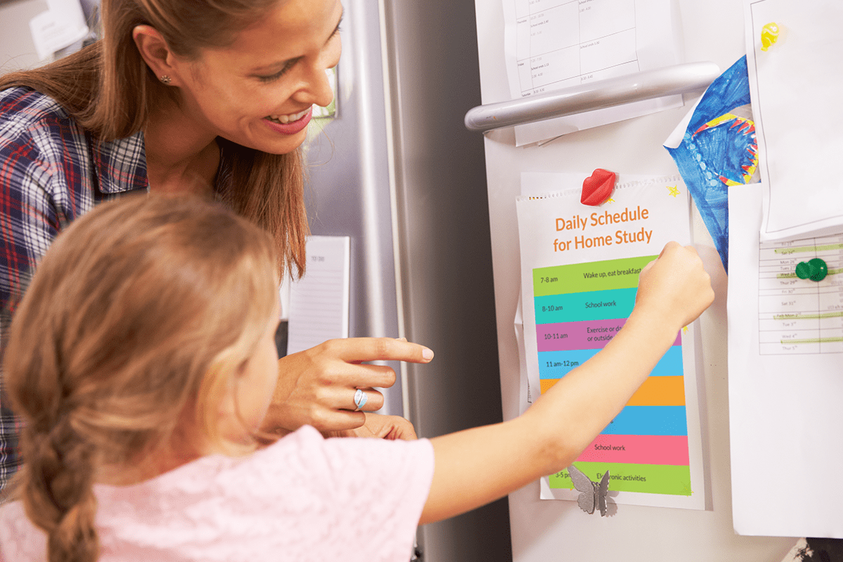 girl and mother looking at a daily schedule on the fridge
