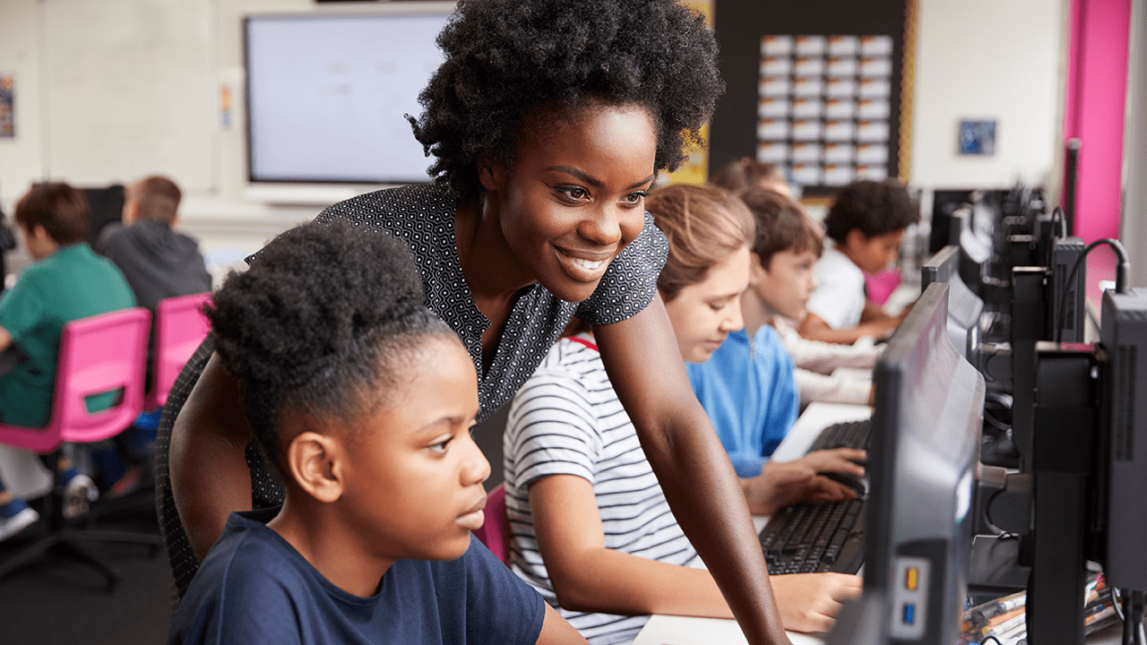 Teacher showing female student something on the computer.