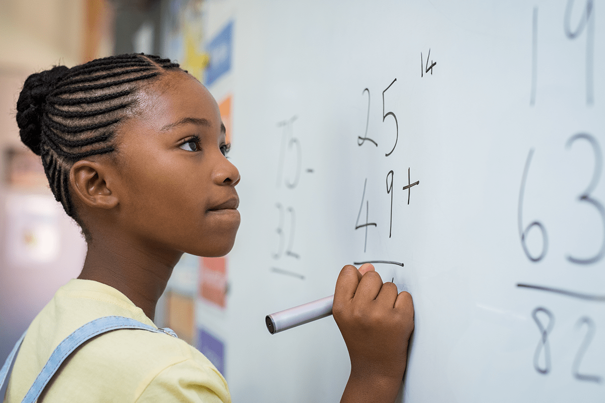 student writing math equations on a whiteboard