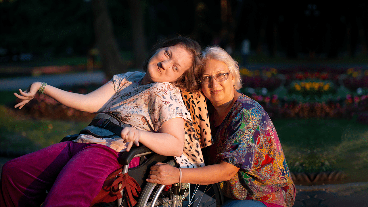 Older mother is hugging adult daughter with special needs.