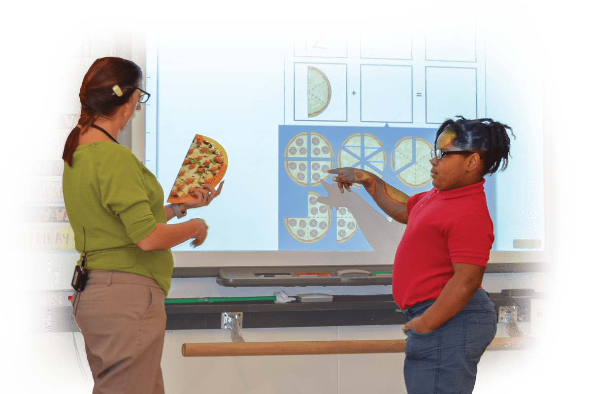 Teacher and student standing at an interactive whiteboard.