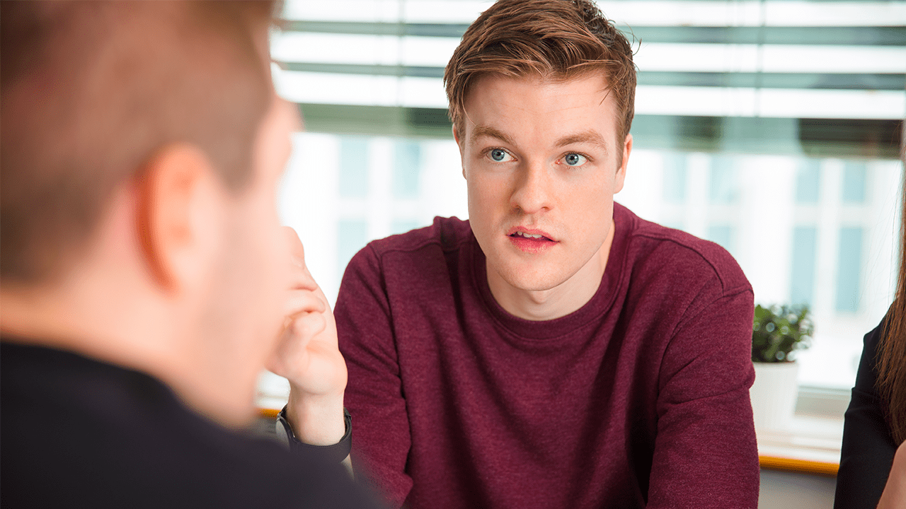 Young caucasian man in a red sweater is talkig to his friend